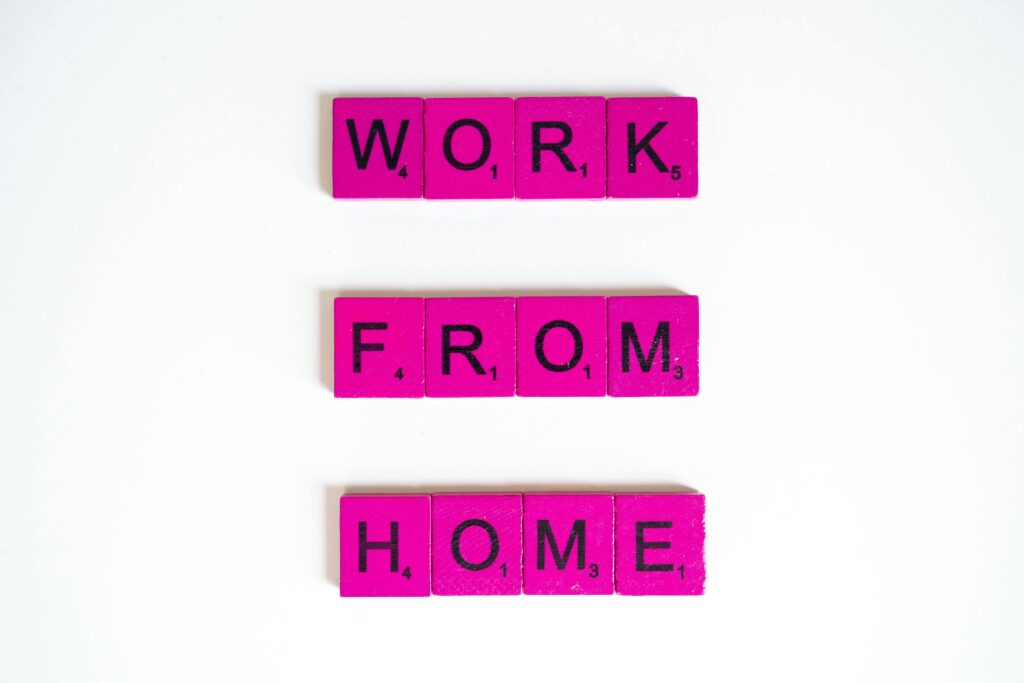 Pink Scrabble tiles spelling 'Work From Home' on a white background, conveying remote work theme.