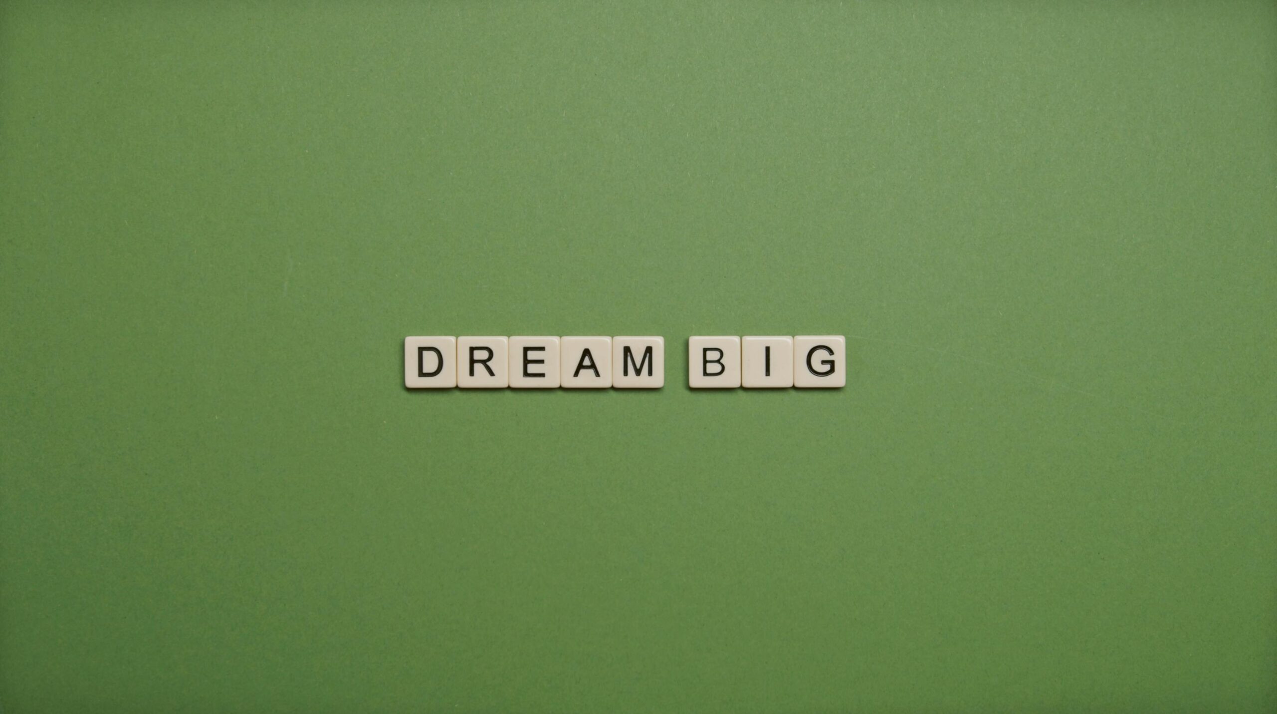 Inspiring 'Dream Big' message with tile letters on a simple green background.