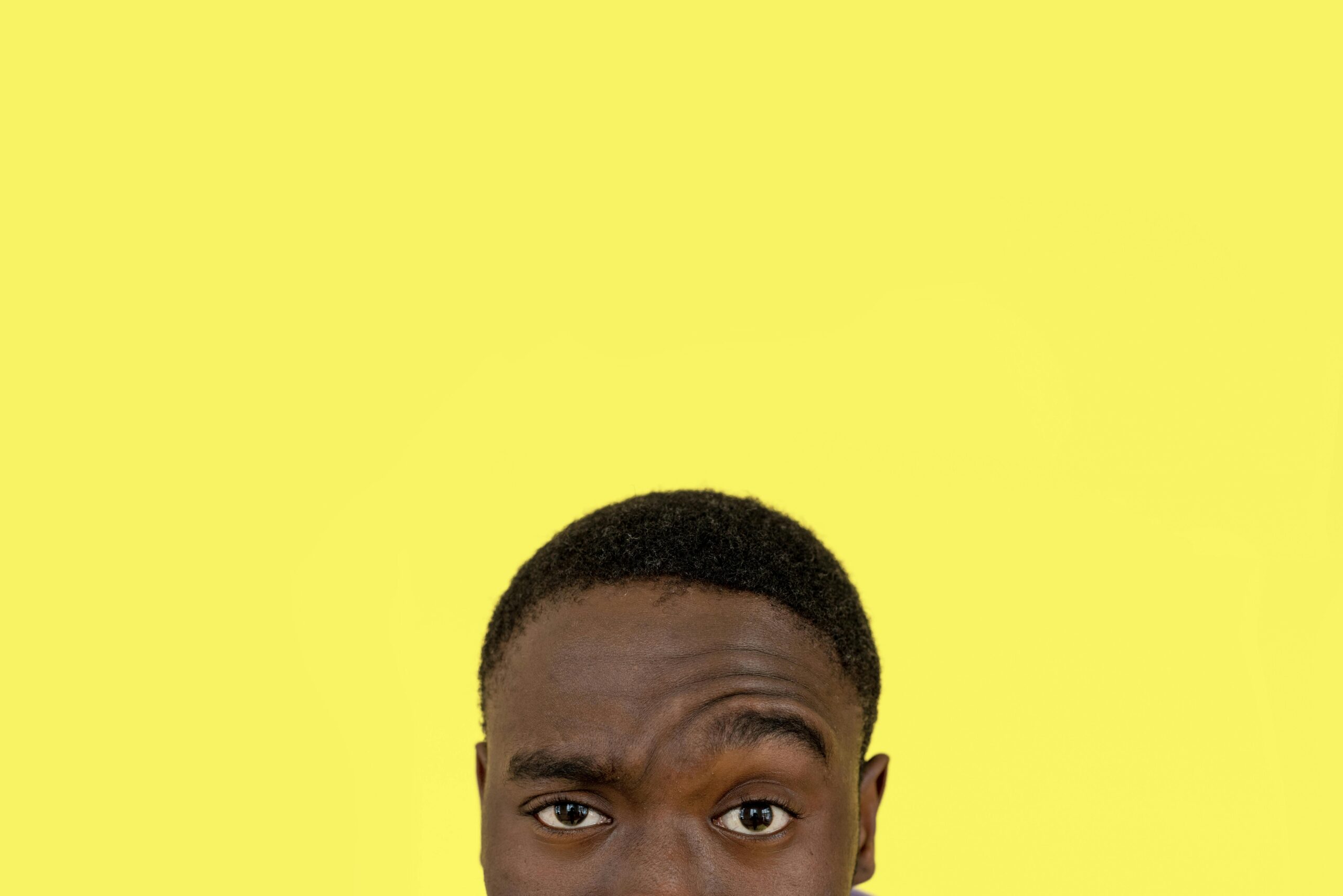 Close-up of a man's face with a thoughtful expression against a yellow background, offering ample space for text.